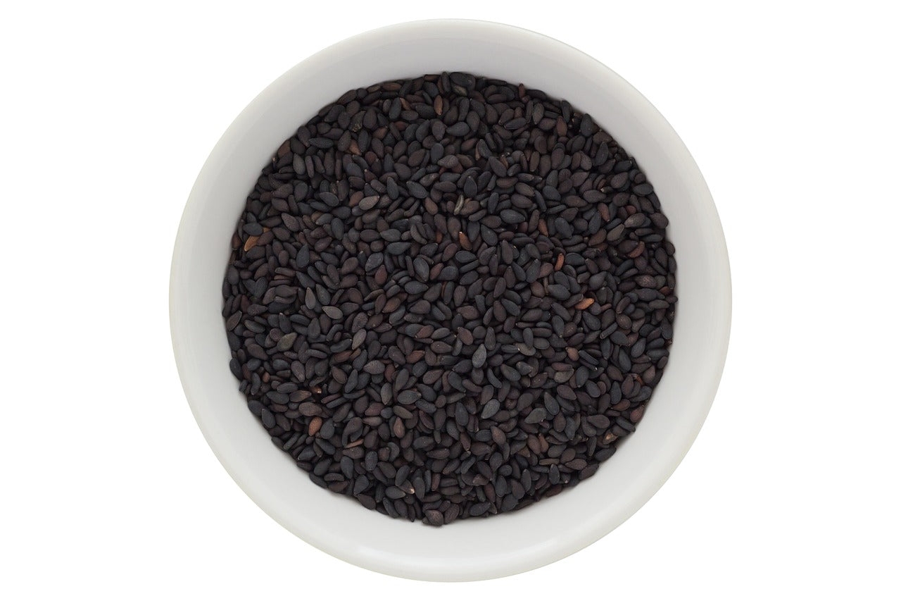 Organic black seeds in a white bowl, commonly used for making black seed oil, known for its various Organic Black Seed Oil Benefits.